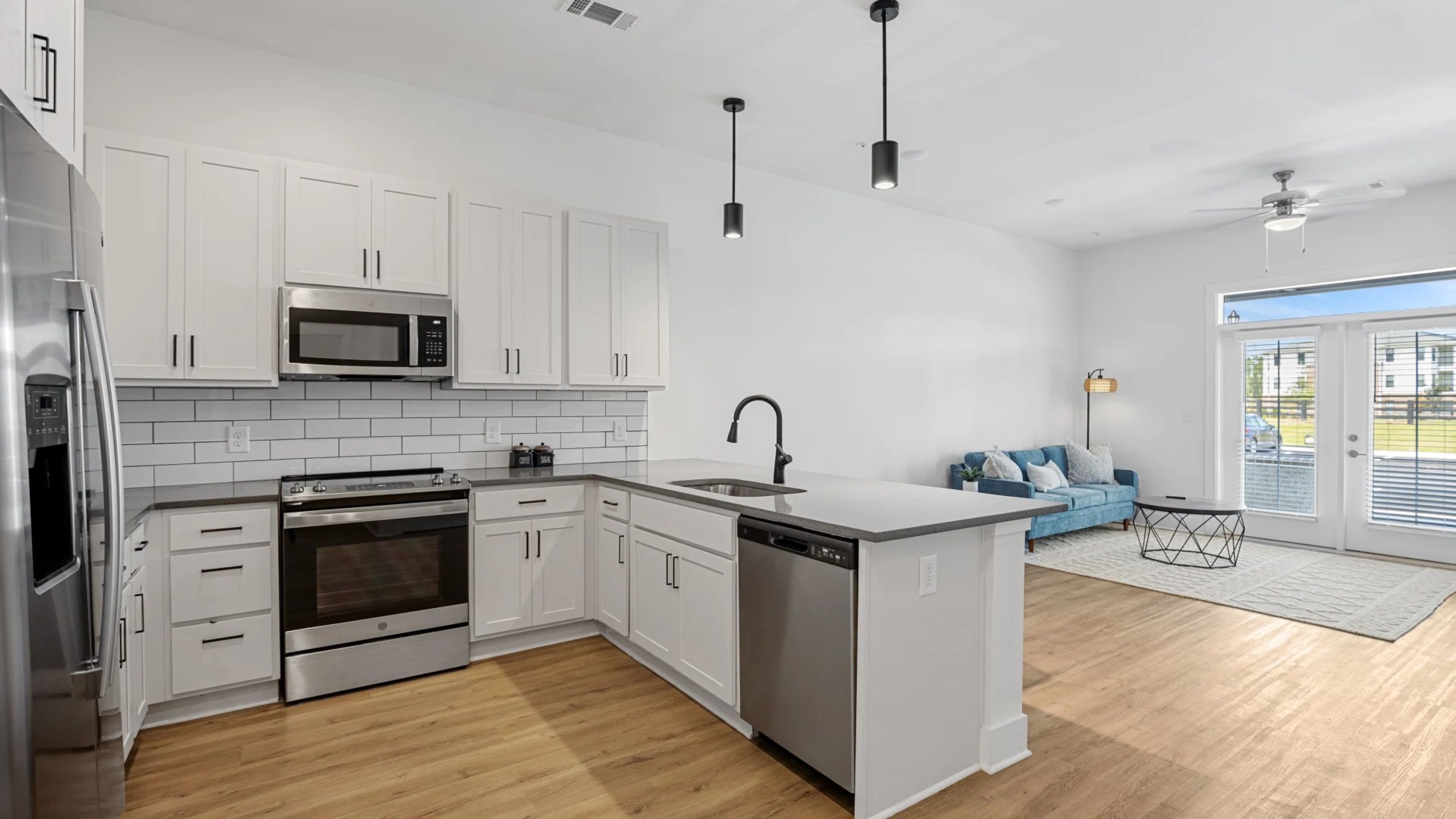 Oak Grove at Blake FarmOak Grove at Blake Farm apartment living space and kitchen with small dining table, kitchen peninsula, and stainless steel appliances