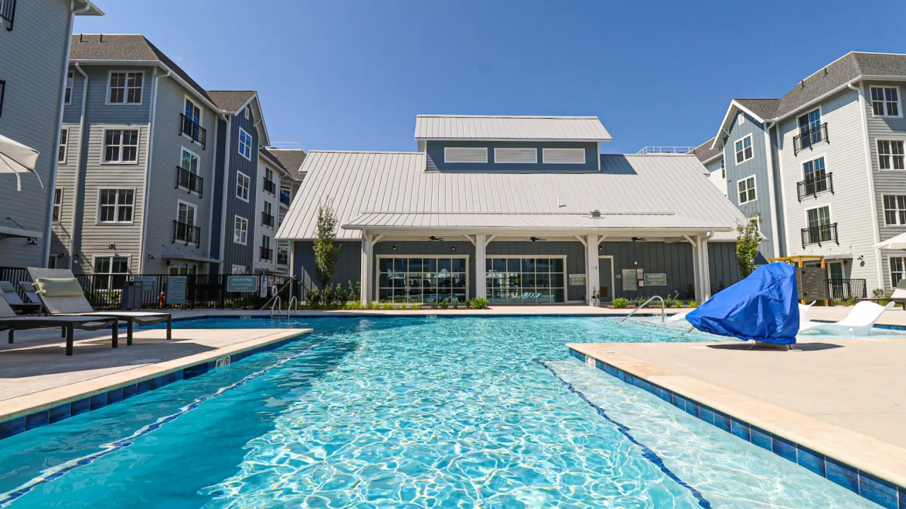 A tranquil pool at the Reserve at Oak Grove at Blake Farm features clear water and inviting lounge areas for guests to enjoy.